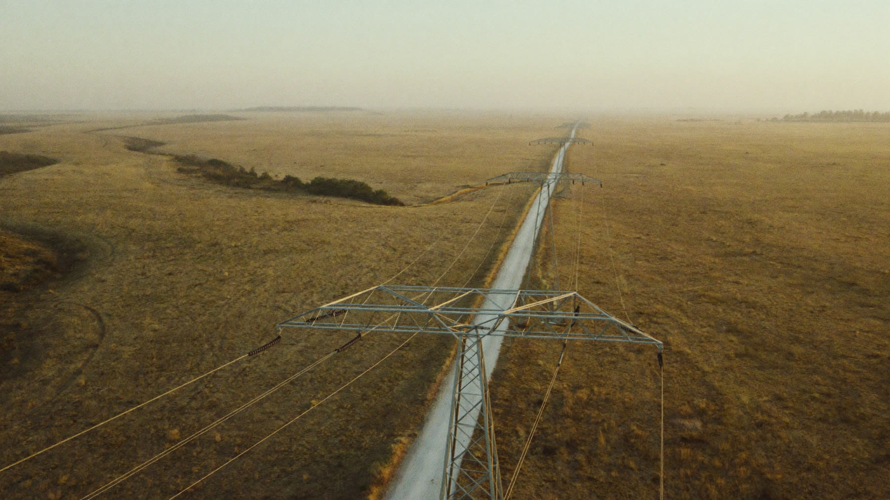 A high voltage transmission line running through open African veld toward the horizon